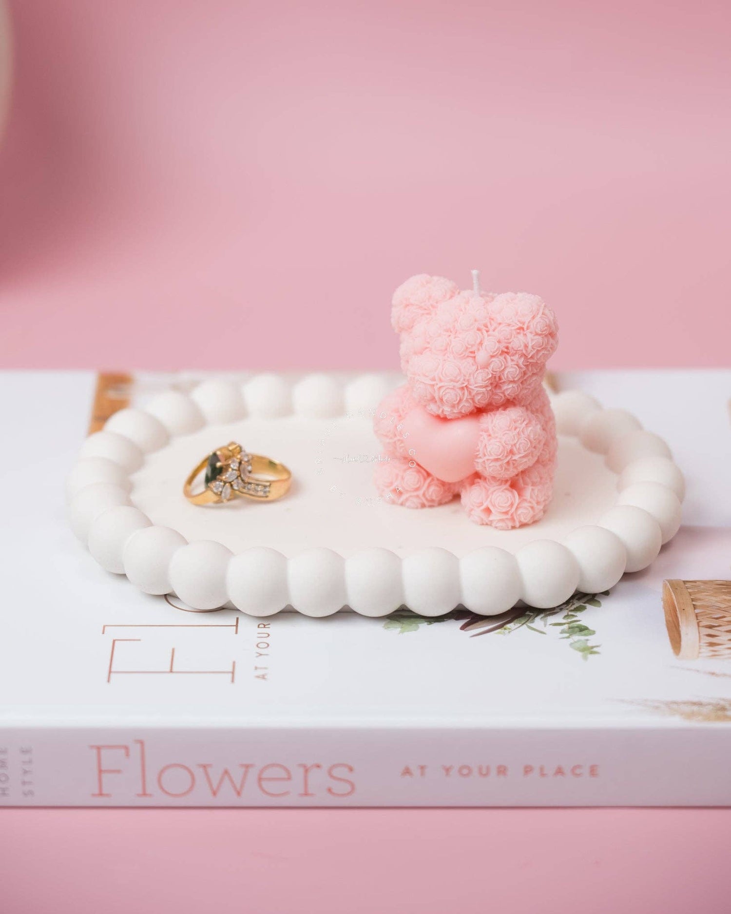 Oval-shaped bubble trinket tray holding a delicate pink teddy bear candle and  gold jewellery pieces.