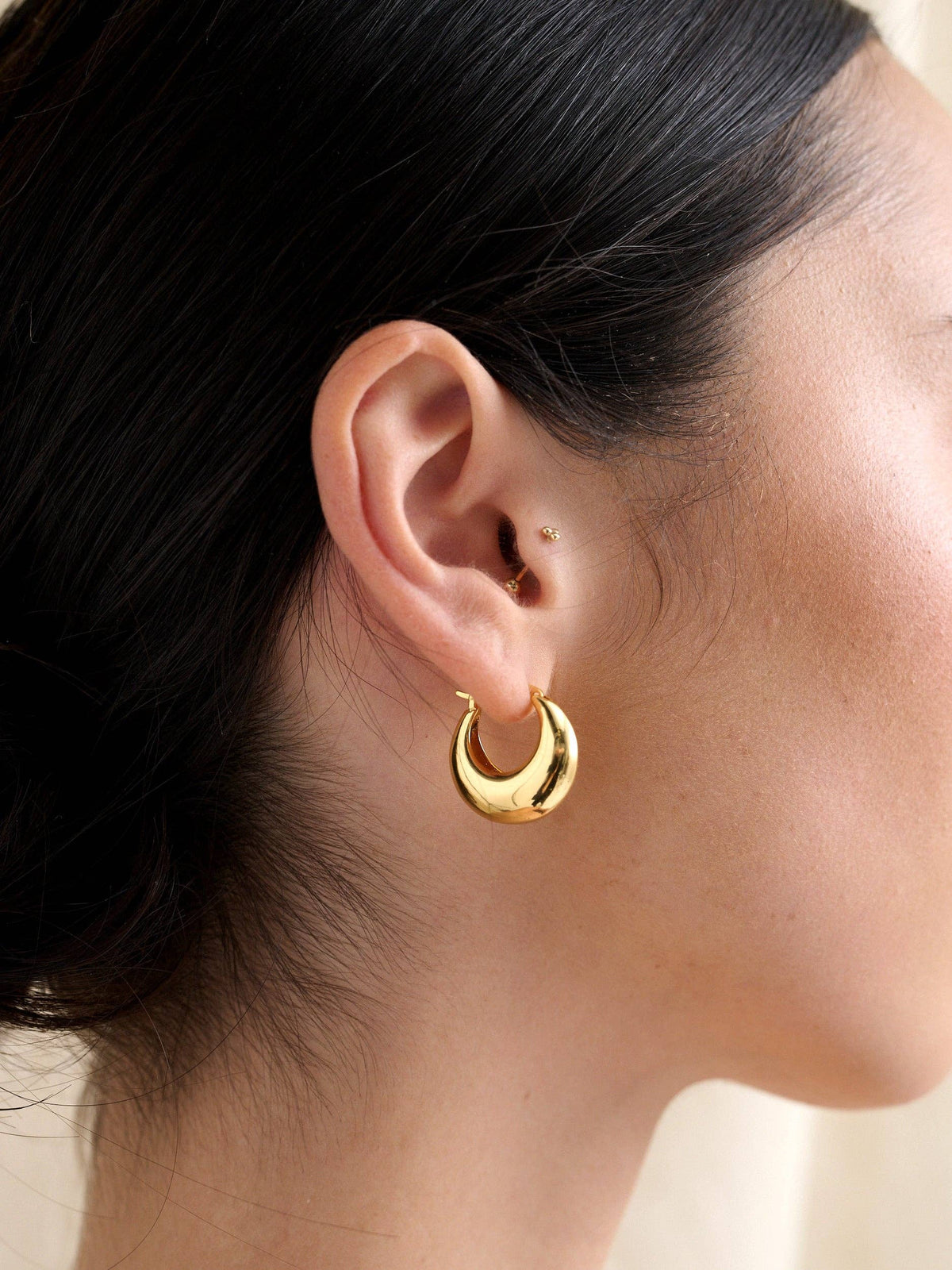 Porte Hoop gold earrings worn by model, side view.