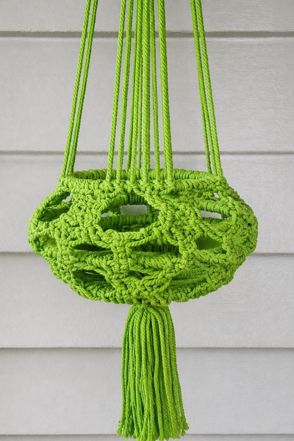 Handmade green macrame plant hanger, side view.