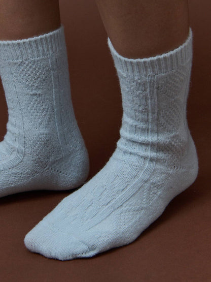 Light blue socks with a textured pattern worn on a brown background