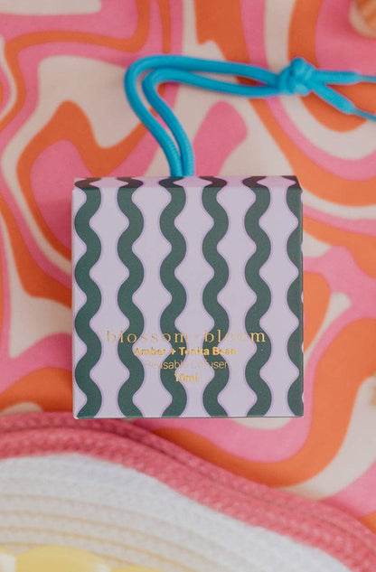 A small diffuser box labeled "blossom + bloom" with a wavy pattern on it and the scent is "Amber + Tonka Bean."