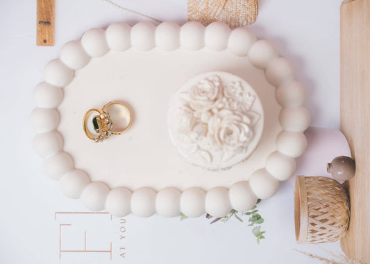 Oval Cream white bubble trinket tray holding gold rings and jewelry dish, surrounded by neutral-toned decor items.