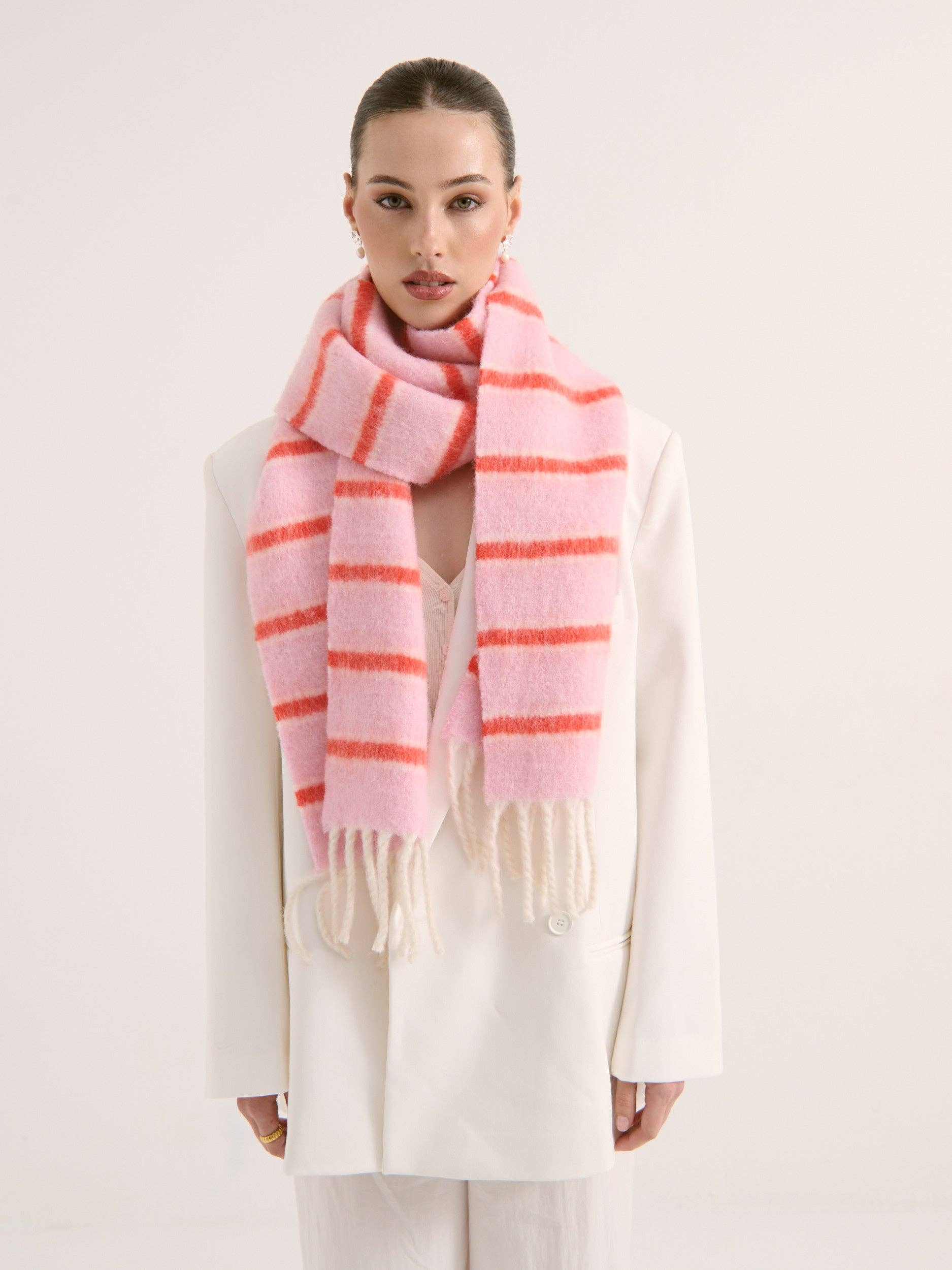 Lady wearing a pink and orange fluffy striped scarf on a white background