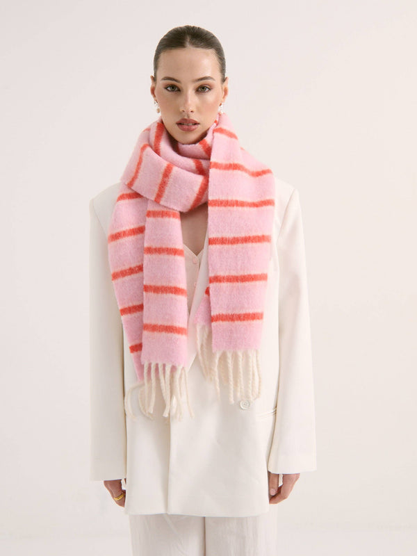Lady wearing a pink and orange fluffy striped scarf on a white background