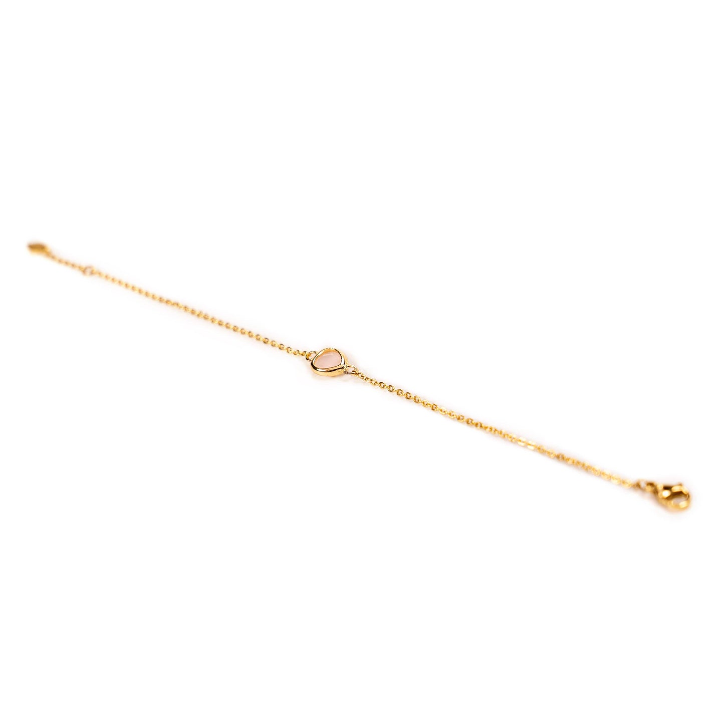 A delicate gold chain bracelet with a small pale pink glass stone in the center and a clasp, shown on a plain white background.