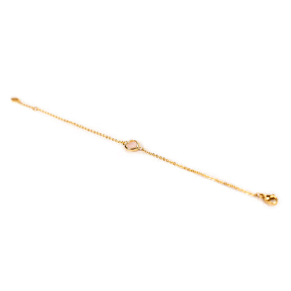 A delicate gold chain bracelet with a small pale pink glass stone in the center and a clasp, shown on a plain white background.