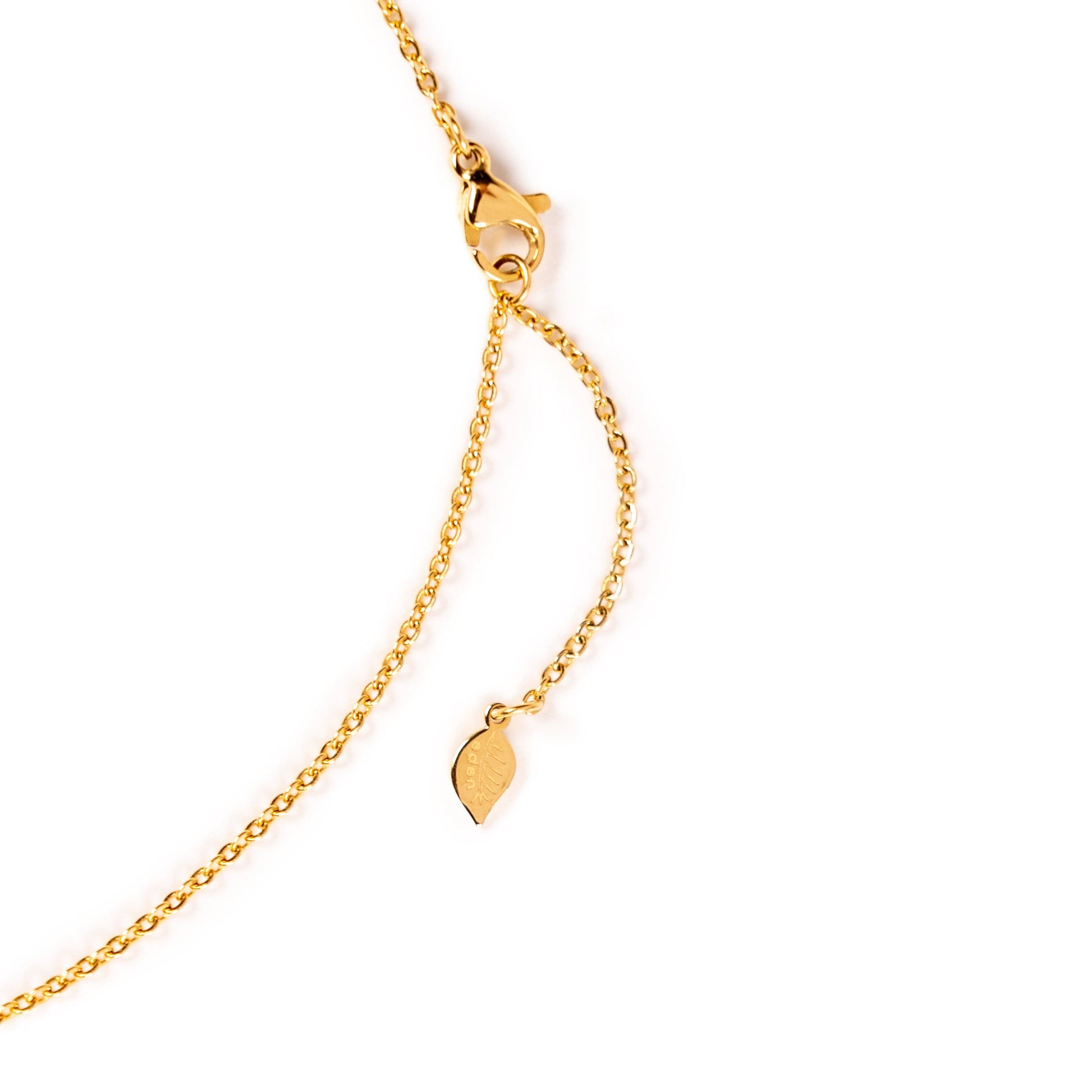A close-up of a Desert Sunrise gold chain necklace with a lobster clasp and a small leaf-shaped pendant, shown on a plain white background.