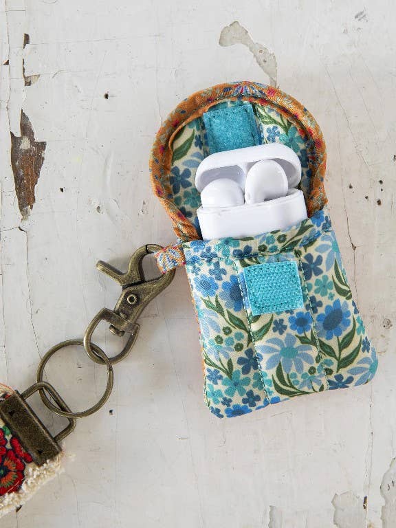 Floral-patterned case with earbuds and keychain on a textured white surface