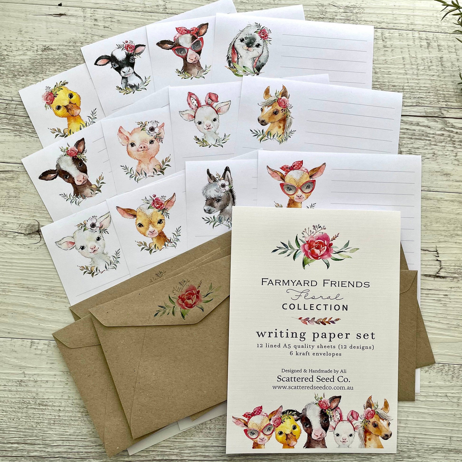 Writing paper set with farm animal illustrations and matching envelopes on a wooden surface.