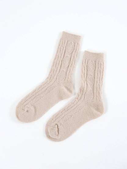 Pair of beige cable knit socks on a white background