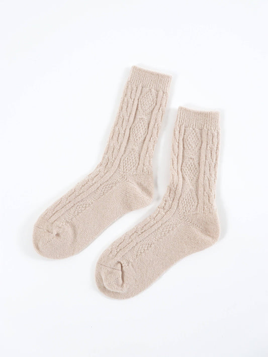 Pair of beige cable knit socks on a white background