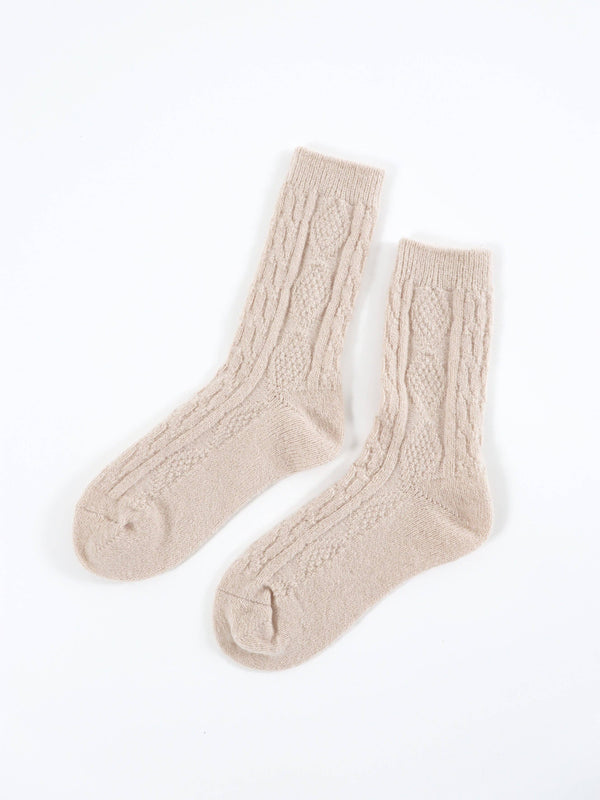 Pair of beige cable knit socks on a white background