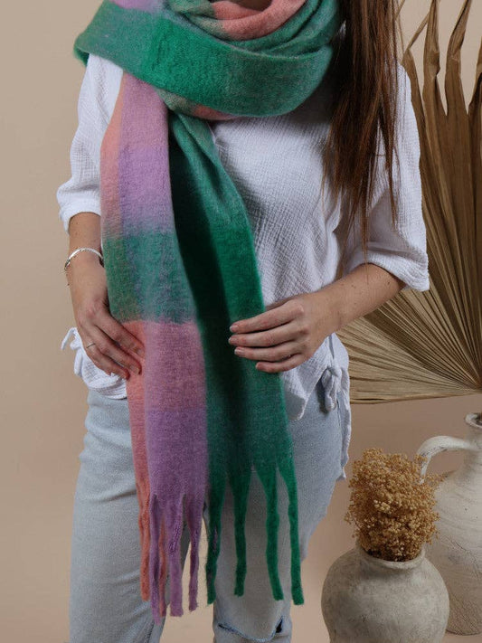 A lady wearing an oversized fluffy scarf in the Alaska-Lollies atyle, featuring a soft, textured fabric with a playful green, pink, and purple pattern.