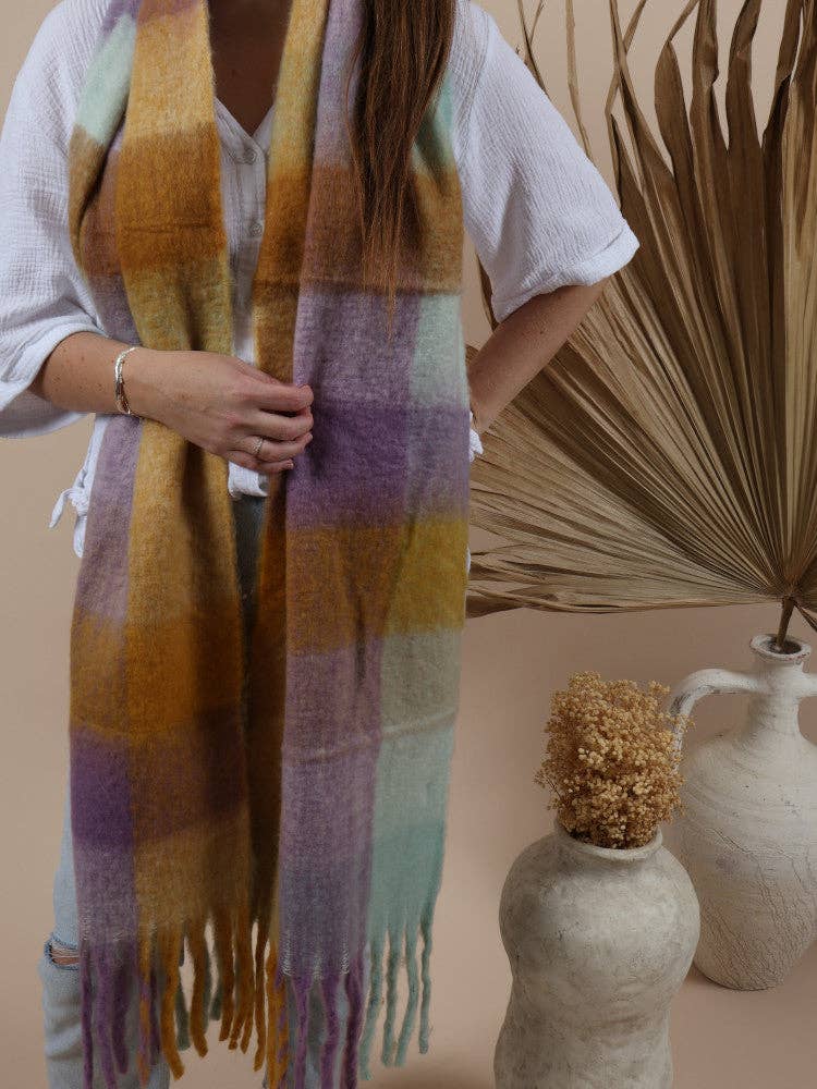 Woman wearing a soft, oversized striped scarf in warm tones, styled for winter comfort and fashion.