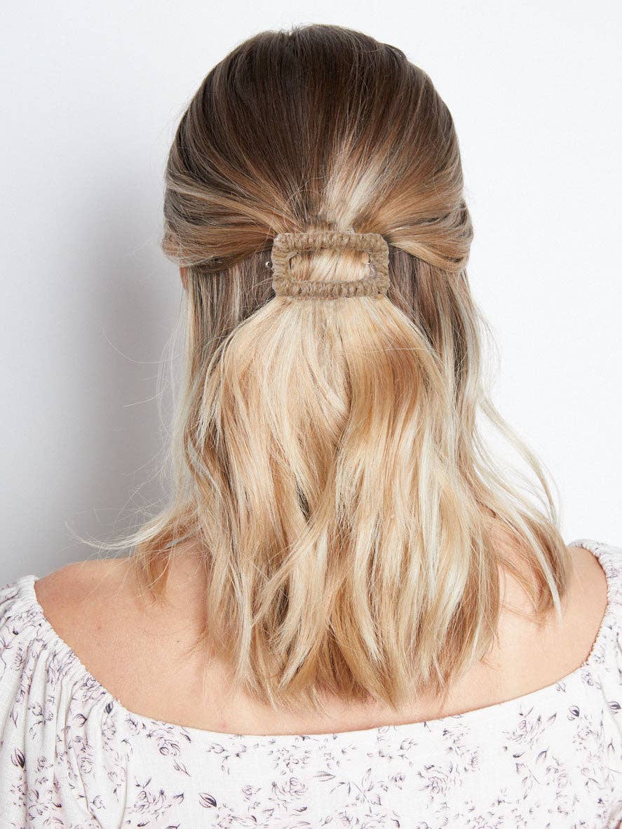 Back view of a blonde lady with a stylish half up hair style, using a decorative ivy twine rectangle hair clip tan colour.