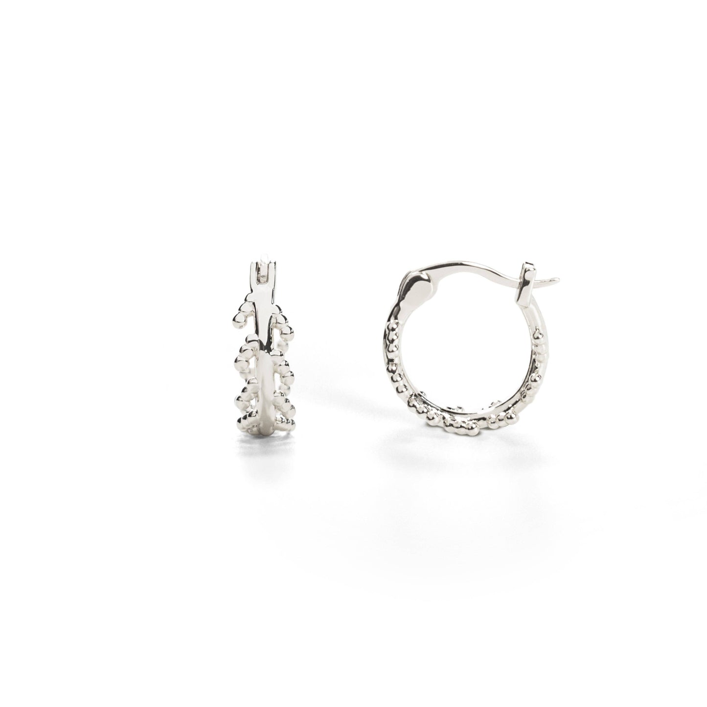 A pair of white gold-plated hoop earrings with an intricate leaf design inspired by the mustard plant.