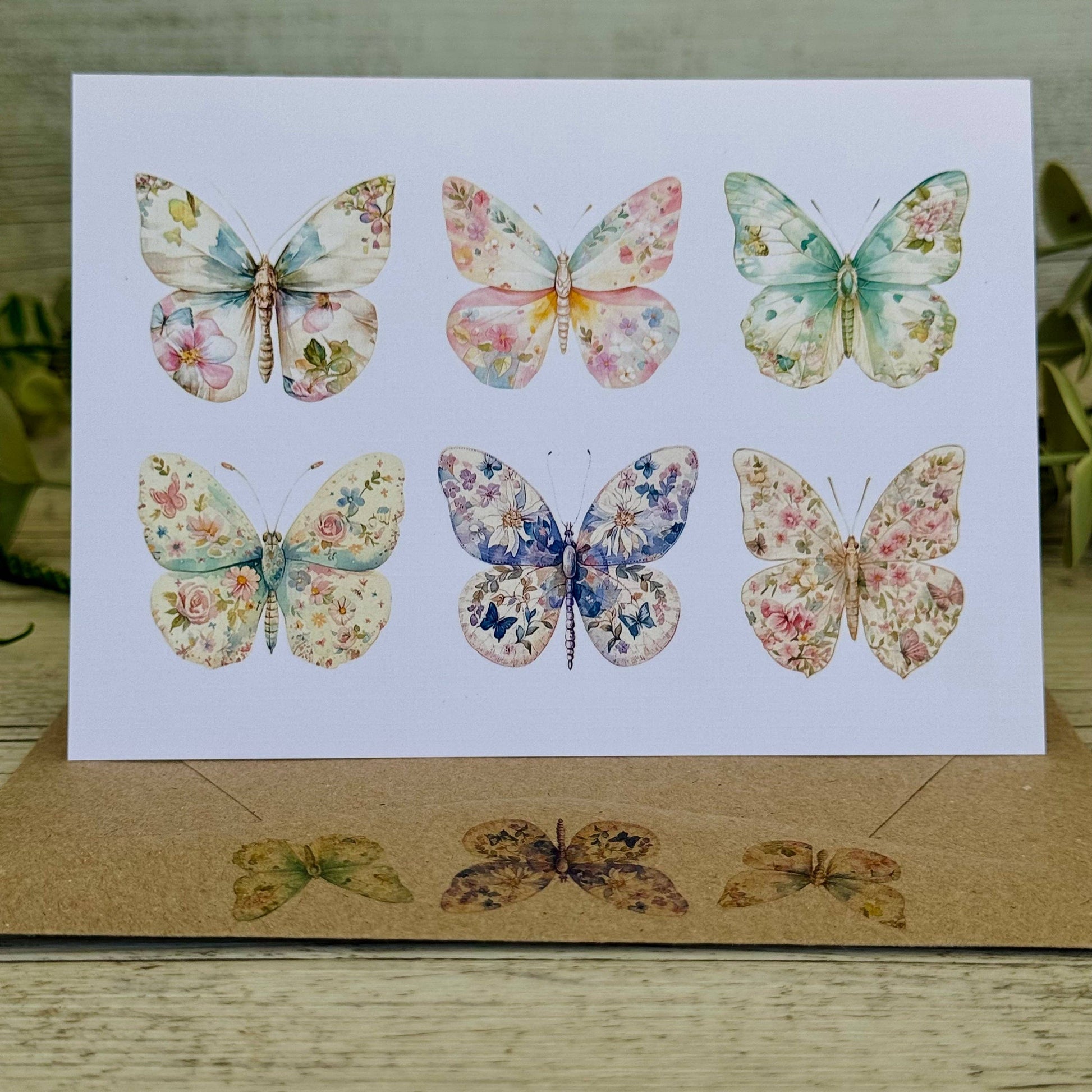 Card  and envelope with floral butterfly illustrations on a wooden surface