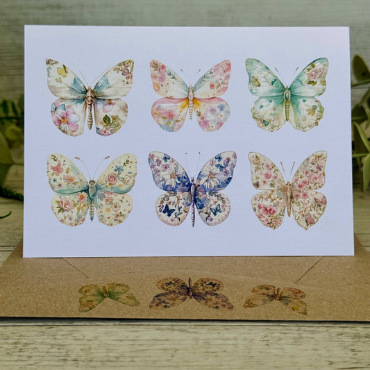 Card  and envelope with floral butterfly illustrations on a wooden surface