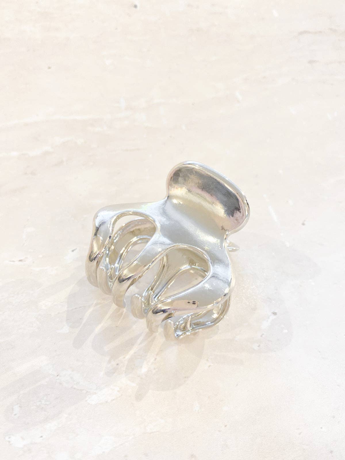 A small silver claw clip with a simple, elegant design, ideal for securing small sections of hair.