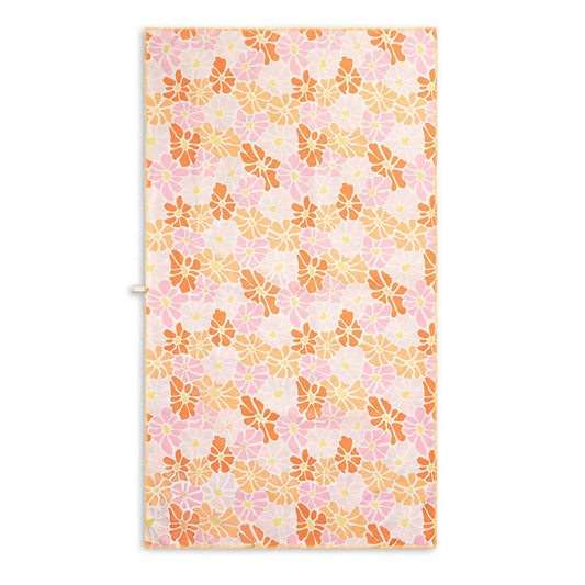 Sand free beach towel featuring a cheerful floral design with red, light orange, and pink flowers, each with yellow centers.