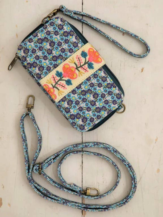 Floral patterned wallet with a detachable strap on a light wooden surface