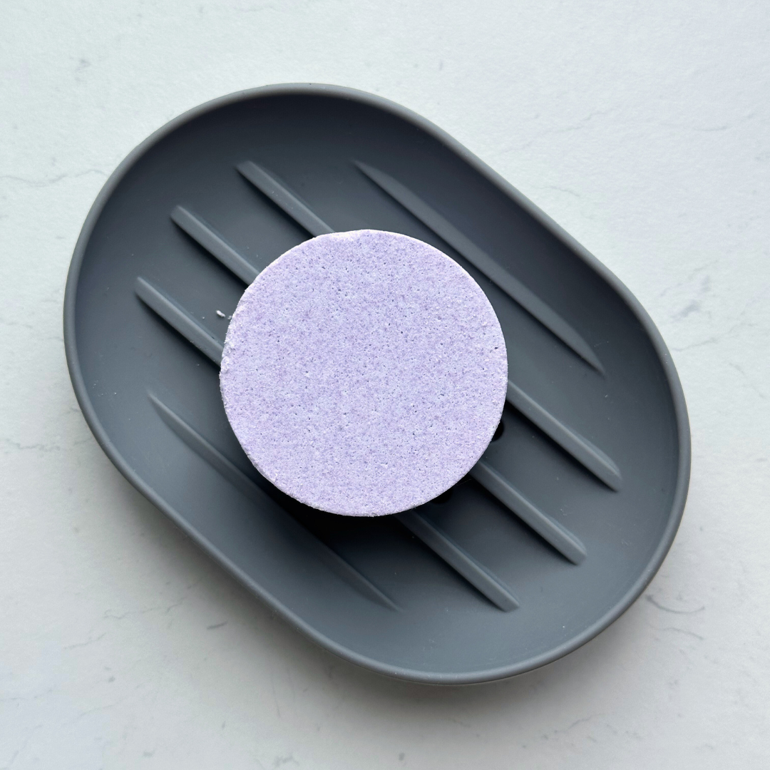Grey silicone shower steamer holder with tablet, angled view.