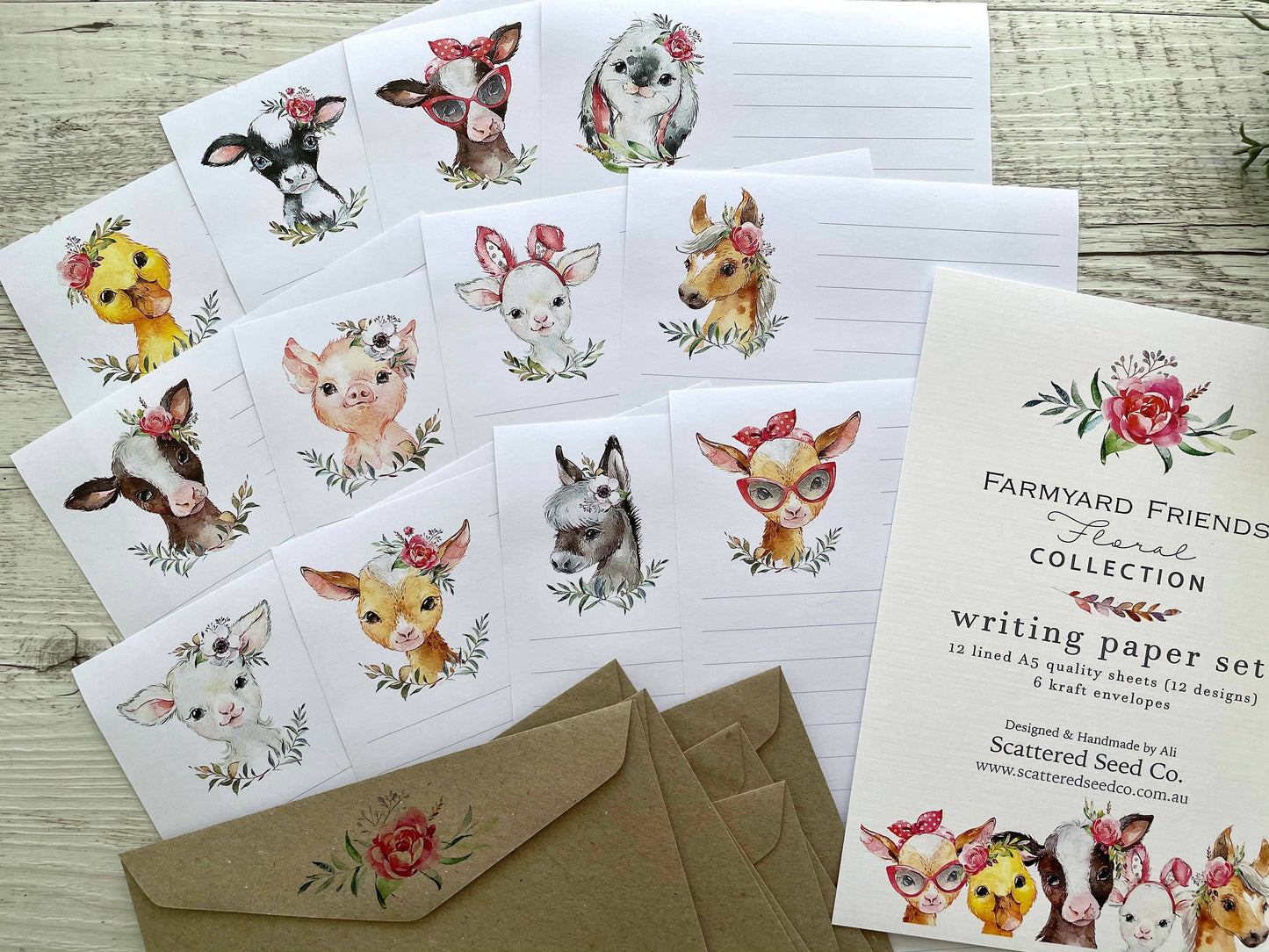 Set of stationery items with farm animal illustrations & florals on a wooden surface